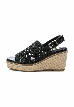 Sandal de cuña trenzado negro con una parte superior texturizada, correa adjustable en el tobillo y una plataforma envuelta en yute. Presenta una silueta curvada.