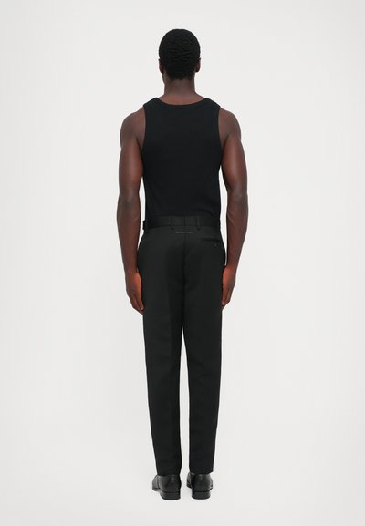Top negru fără mâneci asortat cu pantaloni negri; croi ajustat cu o textură netedă. Pantalonii dispun de un buzunar la spate și de o curea.