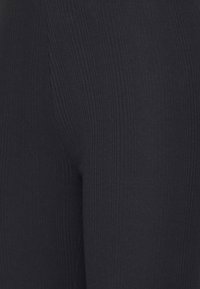 Geribbelde zwarte legging met een textuurafwerking, voorzien van verticale lijnen voor extra detail. Gladde stof, aansluitende pasvorm, enkel lengte.