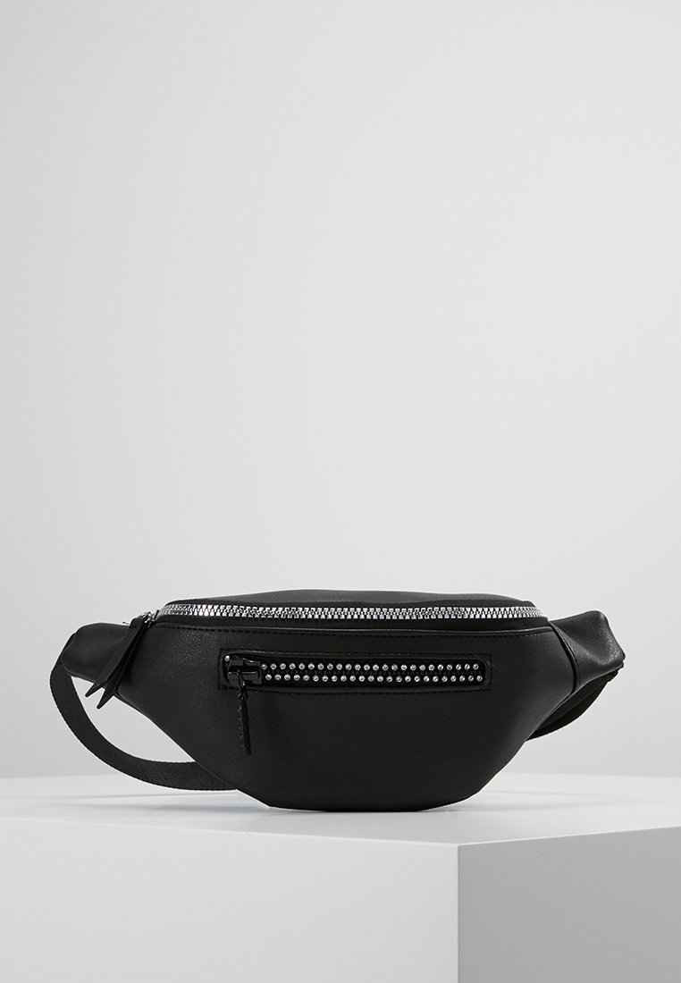 Musta nahkavyölaukku, jossa on kaareva muoto, hopeinen vetoketju ja koristeelliset niittikoristeet. Varustettu etupainetaskulla ja säädettävällä hihnalla.