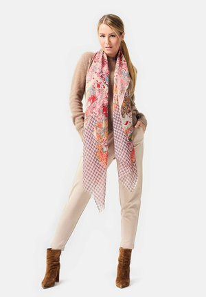 Floral pink and orange scarf with houndstooth accents, framed by a beige sweater and tan pants, paired with brown suede heeled boots.