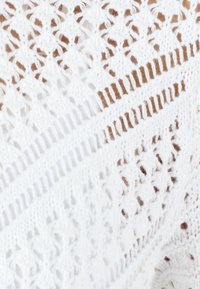 Witte gebreide stof met een openwerk patroon, met verschillende texturen en steken. Intricate kantachtige ontwerp met diagonale lijnen.