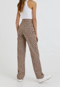 Bruine en crèmekleurige gestreepte hoge taille broek met een wijde pijp, featuring een geometrisch patroon en een gladde textuur. Draag het met witte sneakers.