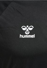 Tela negra con logo blanco estilizado de abeja y el texto "hummel" impreso debajo.