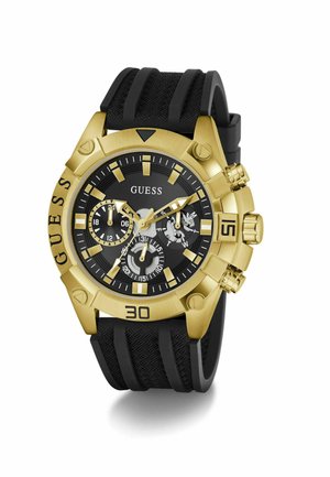 Zlaté hodinky Guess s čiernym textúrovaným ciferníkom, tromi subciferníkmi, čiernym textúrovaným silikónovým remienkom a výraznými číselnými značkami na lunete.