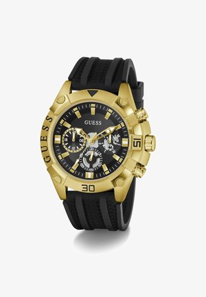 Ročna ura Guess v zlati barvi z črnim teksturiranim številčnico, tremi podštevilčnicami, črnim teksturiranim silikonskim paščkom in izrazitimi številčnimi oznakami na okvirju.