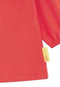 Rotes Baumwoll-T-Shirt mit rundem Halsausschnitt und kurzen Ärmeln. Ein kleines gelbes Etikett mit Markendetails ist am Saum befestigt.