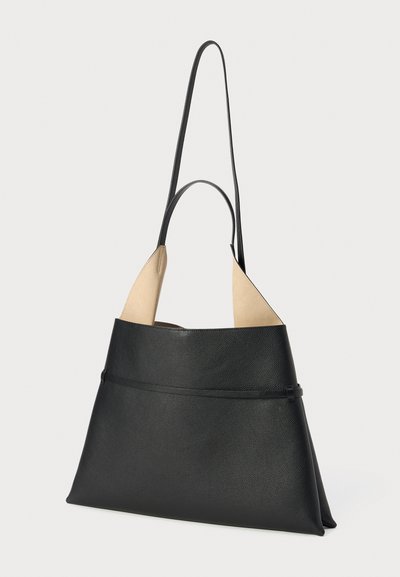 Bolsa tote de cuero negro con acentos beige, que presenta una forma triangular estructurada, correas largas y una textura suave. Detallada con una costura sutil.