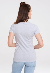 Gray short-sleeve t-shirt, cotton blend, fitted design. Smooth texture, rounded neckline, visible stitching, worn with light blue jeans.
