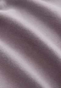 Tissu lisse de couleur violet clair avec une texture douce ; présente des motifs subtils et un tombé doux, indiquant un textile extensible.