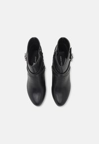 Botines de cuero negro con un diseño elegante, puntera afilada y cierre de cremallera lateral. Presenta una pequeña hebilla decorativa en el lado exterior.