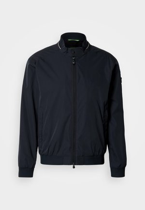 Granatowa kurtka bomberka, lekki materiał, ściągacze na rękawach i u dołu, stójka, dwie boczne kieszenie oraz przedni zamek błyskawiczny. Minimalistyczny design.