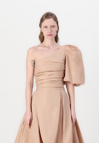 One-shoulder, puff-sleeve dress in light beige fabric; features gathered texture and a fitted bodice flowing into a full skirt.
