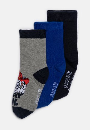 Tre par sokker i grå, blå og svart. Den grå sokken har et grafisk design med et skjelett og en rød hatt. Hver sokk har ribbet topp.