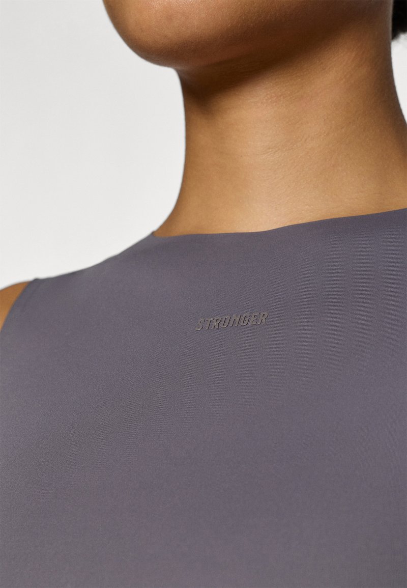 Top ajustado sin mangas en una tela de color púrpura suave. Presenta una textura lisa con un sutil logo en relieve de "STRONGER" en la zona del pecho.