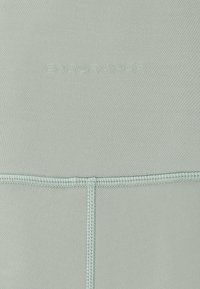 Ljusgrön badklädes tyg med slät textur, som har ton-i-ton sömmar och ordet "ENDURANCE" präglat nära toppen.