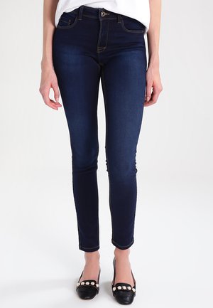 Dark blue skinny jeans made of denim, featuring yellow stitching, a mid-rise waist, and a classic five-pocket design.