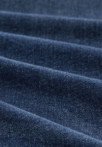 Tessuto in denim blu scuro con texture visibile e un sottile motivo a macchie, presentato in strati piegati, evidenziando spessore e trama.