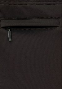 Black athletic fabric featuring a discreet zipper pocket at the top, with smooth texture and fine stitching details.
