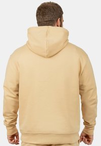 Felpa con cappuccio beige dal design semplice, con tasca a marsupio e polsini a coste. Texture morbida e vestibilità comoda.