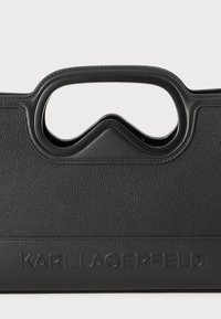 Borsa a mano nera con struttura rigida, realizzata in pelle testurizzata, dotata di manico curvo e logo impresso, con accenti lisci in contrasto.