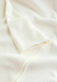 White ribbed fabric with a soft texture, featuring a smooth drape and subtle sheen, showcasing gentle folds and curves.