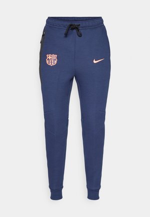 Mørkeblå sweatpants med elastiske manchetter, prydet med et rosa logo og Barcelonas skjold, sidelommer og sorte sidelægningsdetaljer.