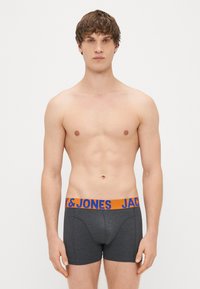 Šedé boxerky s elastickým páskem v oranžové a modré barvě, na kterém je natištěno "JACK & JONES". Tkanina vypadá hladce a přiléhavě.