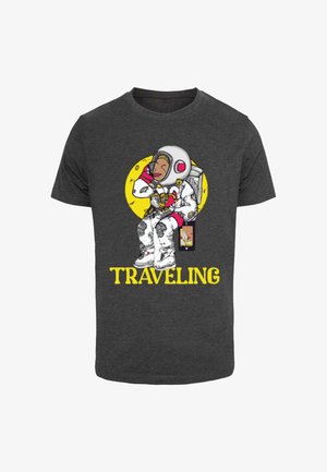 Czarnawy t-shirt z graficznym motywem astronauty na tle żółtego okręgu; napis "PODRÓŻUJĄC" w pogrubionym żółtym poniżej, zabawne elementy projektu.