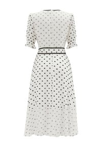 Robe blanche à pois noirs, manches courtes bouffantes, taille cintrée avec ceinture et ourlet évasé. Fermeture éclair au dos.