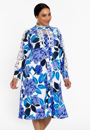 Blumenkleid in Blau- und Weißtönen, mit aufwendiger Spitzenborte an den Ärmeln, Knopfleiste vorne und knielangem Schnitt mit lässiger Passform.