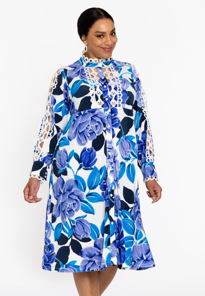 Bloemig jurkje met blauw en wit kleuren, ingewikkelde kantafwerking op de mouwen, knopen aan de voorkant en een knie-lange snit met een ontspannen pasvorm.