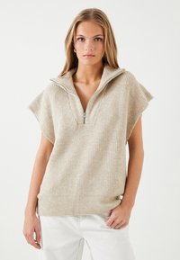 Beige, ribbet sweater med halv-lynlås krave og brede ærmer. Tekstureret stof med en afslappet pasform, designet til lagtydning.