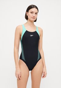 Μαύρο μαγιό με τυρκουάζ λεπτομέρειες, που διαθέτει σχέδιο racerback, ζιγκ ζαγκ μοτίβα στα πλάγια και λογότυπο στη στήθη.