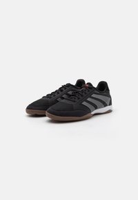 Czarne buty sportowe z siateczkowego i zamszowego materiału, z szarymi paskami, sznurowanym zapięciem i brązową gumową podeszwą.