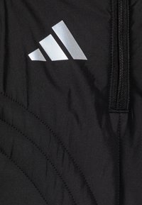 Czarna kurtka z pikowanym wzorem, z logo Adidas w kolorze srebrnym. Zamek z przodu. Materiał wydaje się gładki i lekki.