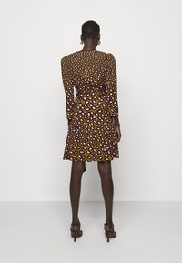 Braun Kleid mit pinkem Leopardenmuster, langen Ärmeln und ausgestellt geschnittenem Saum. Hergestellt aus einem glatten Stoff mit tailliertem Oberteil und gerafftem Taillendetail.