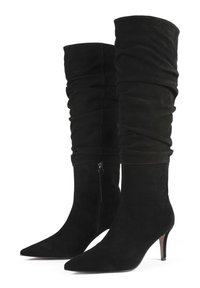 Botas altas de ante negro hasta la rodilla con punteras puntiagudas, detalle de fruncido en el eje, cremallera lateral y tacones finos de altura media.