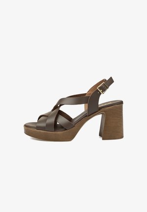 Sandalia de cuero marrón con tacón alto, correas cruzadas, hebilla ajustable en el tobillo y tacón grueso de plataforma de madera.
