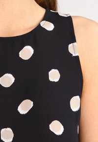 Top nero senza maniche con grandi pois beige a pennellate, dotato di scollatura rotonda e tessuto morbido.