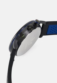 Reloj analógico negro con caja redonda, acentos azules, correa texturizada negra y herrajes plateados. Incluye tres botones de presión en el lateral.