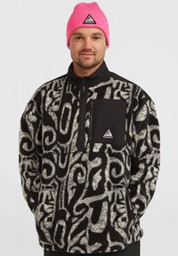 Pull en polaire noir et gris avec des motifs abstraits, demi-zip au niveau du cou, et poche poitrine noire. Bonnet à côtes rose avec logo.