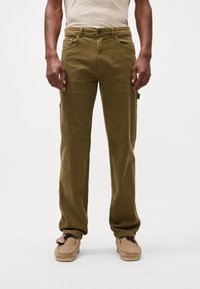 Khaki cargo bukser med en afslappet pasform, der har for- og sidelommer, lynlås og knappelukning. Blødt, struktureret stof.
