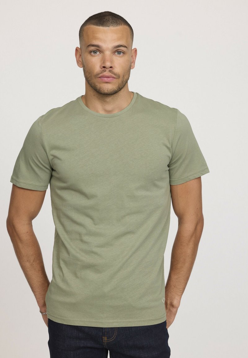T-shirt vert à col rond en tissu doux, à manches courtes, coupe slim, avec une texture lisse et sans motifs ni accents visibles.