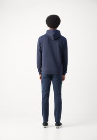 Sudadera navy con bolsillo canguro y capucha con cordón, combinada con pantalones cargo navy; ambos presentan una textura de tela suave.