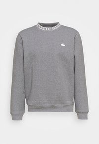Grå långärmad sweatshirt med ribbade manschetter, en hög krage med vit "LACOSTE"-text och en liten vit krokodil-logotyp på bröstet.