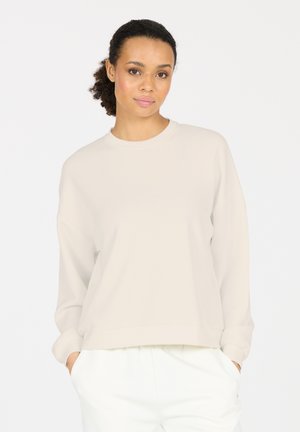 Helle beigefarbene Sweatshirt mit rundem Ausschnitt und überschnittenen Schultern. Hergestellt aus weichem Stoff, mit gerippten Bündchen und lockerem Schnitt.