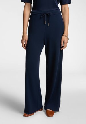 Pantaloni a gamba larga blu navy in un tessuto morbido con vita elastica e cordoncino, caratterizzati da dettagli dorati. Texture liscia con striscia bianca sui lati.