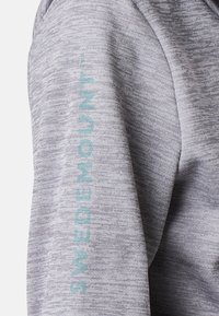 Pullover grigio con tessuto texturizzato. Presenta un logo "SWEDEMOUNT" blu chiaro ricamato in verticale sulla manica destra.