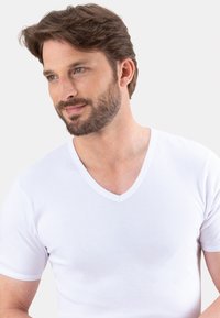 T-shirt en coton blanc à col en V, à manches courtes et d'une texture lisse. Présente un design classique avec des coutures minimales et une coupe ajustée.